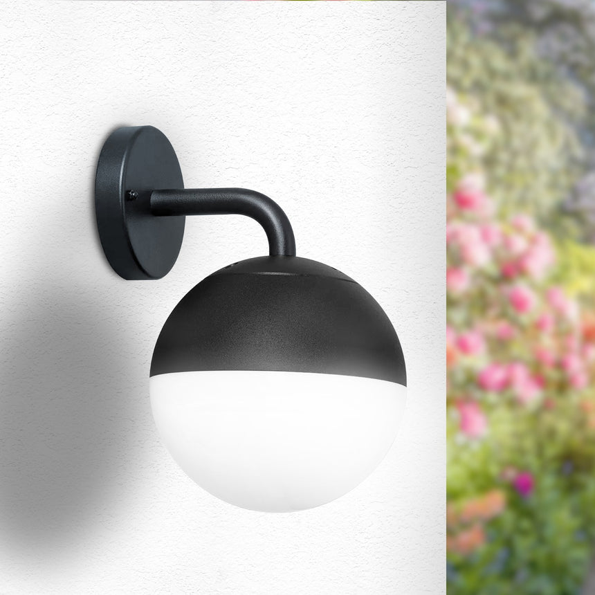 Aplique de exterior LEDME Cam LM6168 negro con difusor blanco, instalado junto al jardín