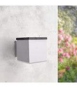 Aplique solar LEDME Jano LM6439 blanco instalado en una pared exterior, vista de día